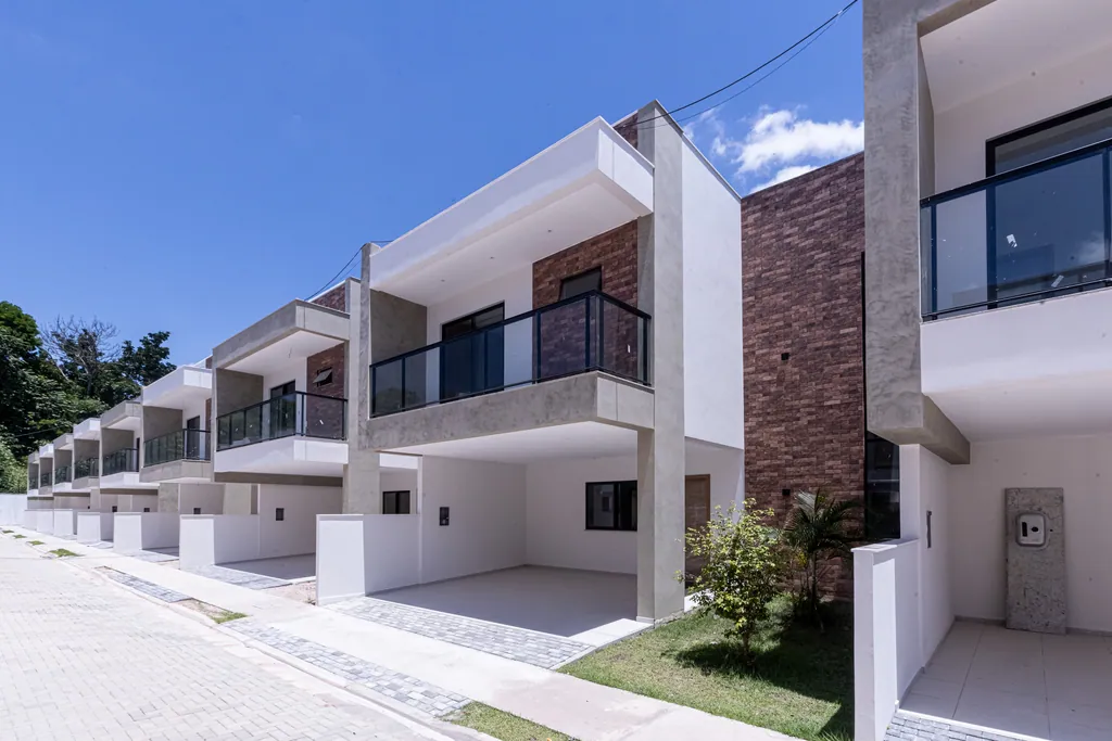 Foto das casas do Tree Residence em dia de sol, com varandas de vidro e garagem coberta